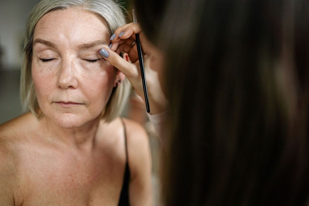 Older woman having makeup applied with a brush