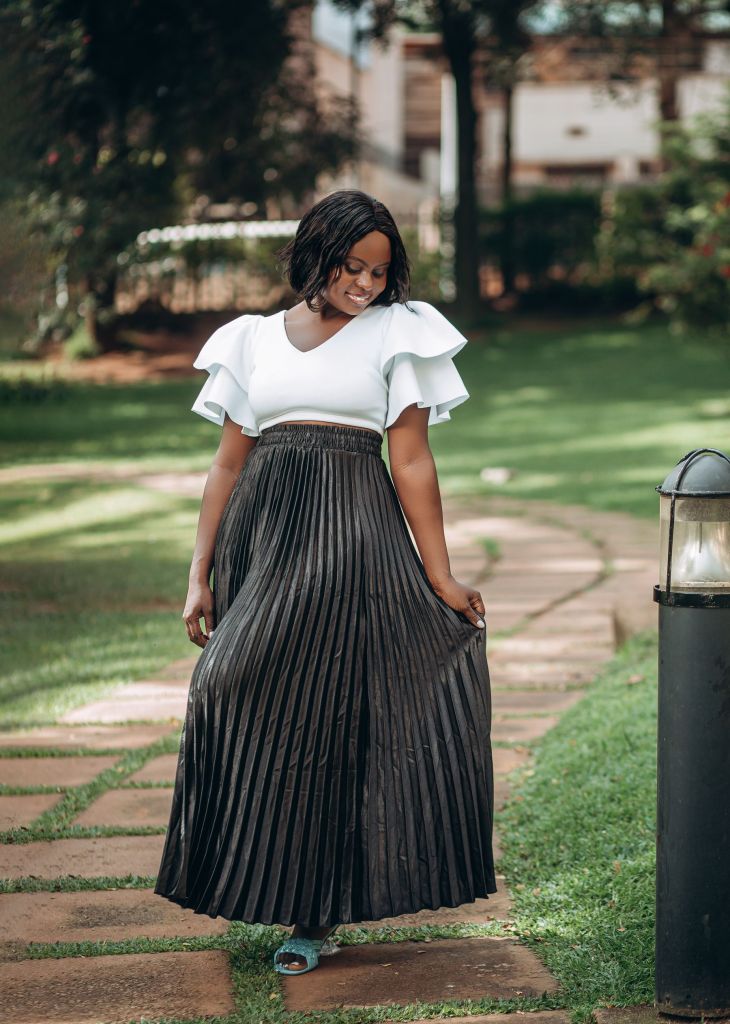 Woman in a white top and long black skirt walking along a park path