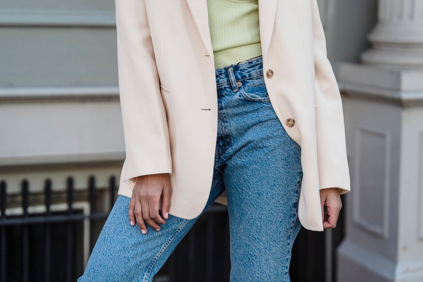 Cream tailored blazer worn over a pale green top with blue jeans.